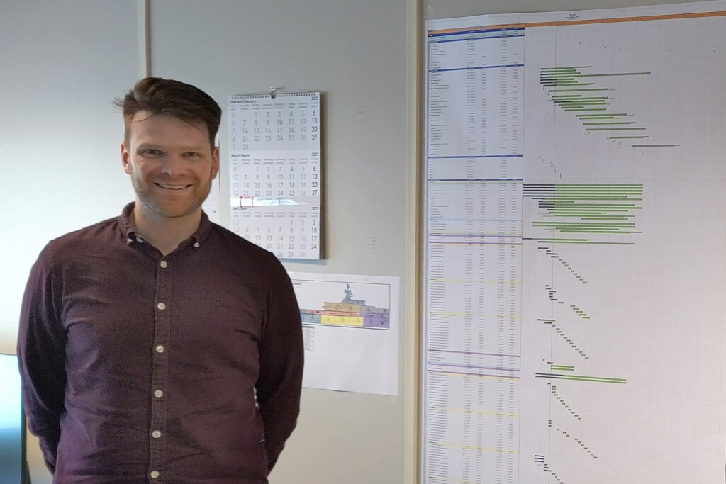 Production coordinator Stan Haag stands next to the planning document for the construction of the Hybrid Expedition Yacht YN 478.