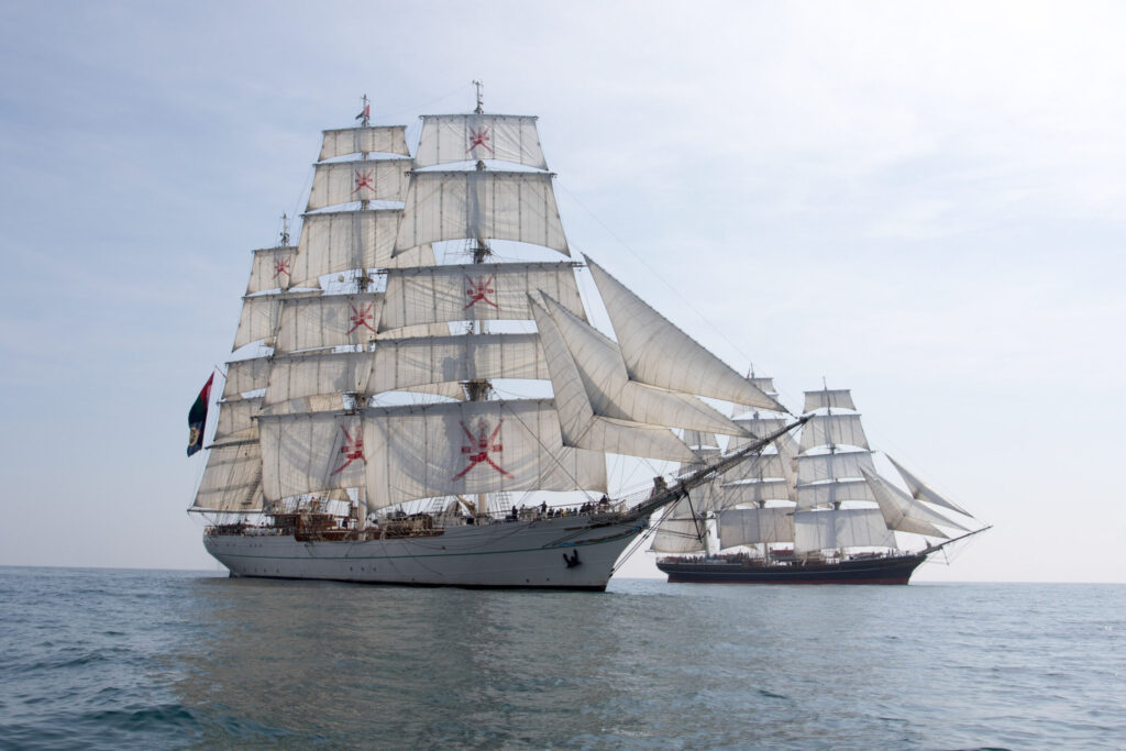 De Shabab Oman II vaart naast de Clipper Stad Amsterdam, wiens bemanning destijds heeft geholpen met de sea trials.